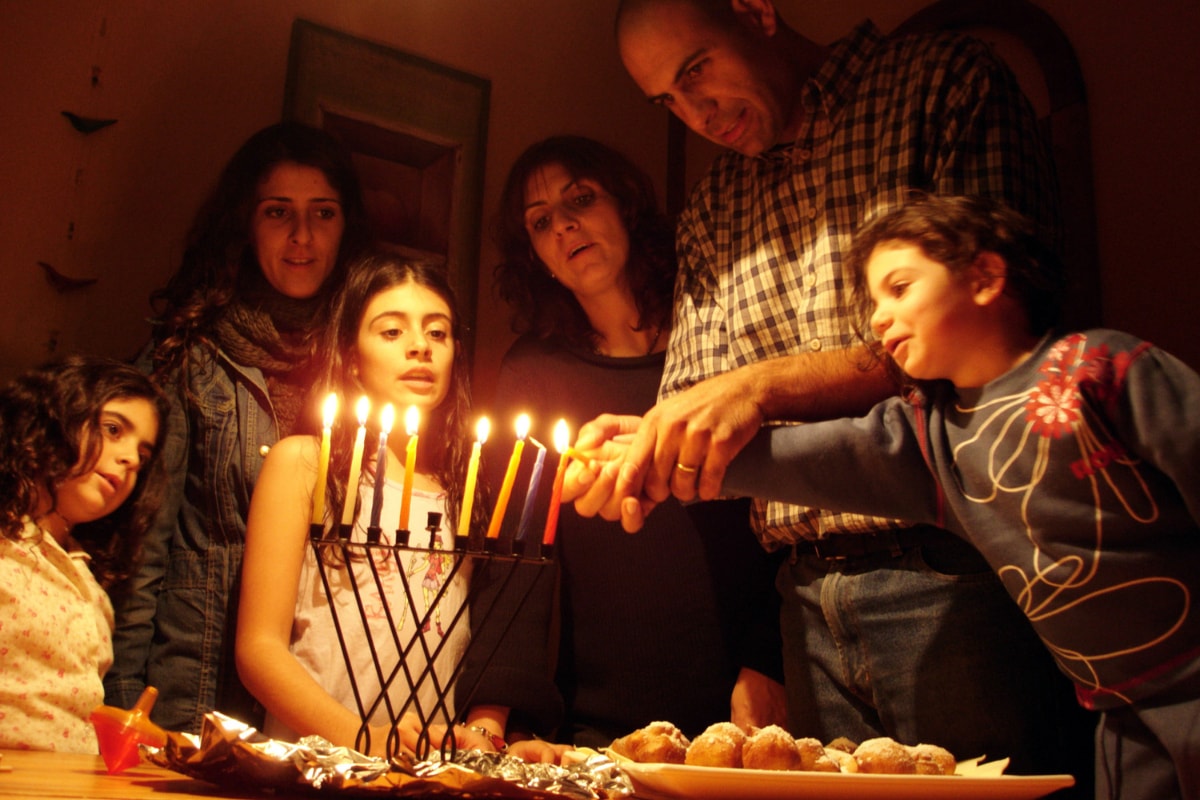 family lighting menorah on hanukkah