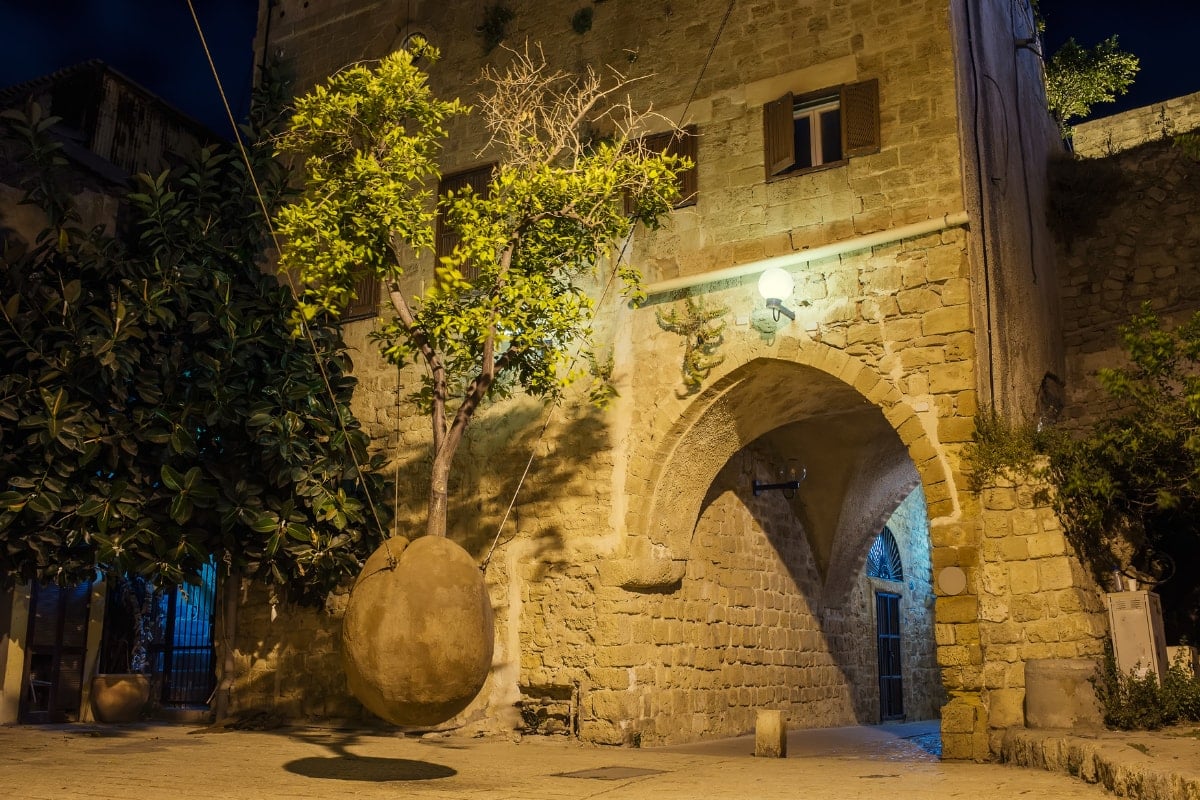 a suspended orange tree with a stone building behind it