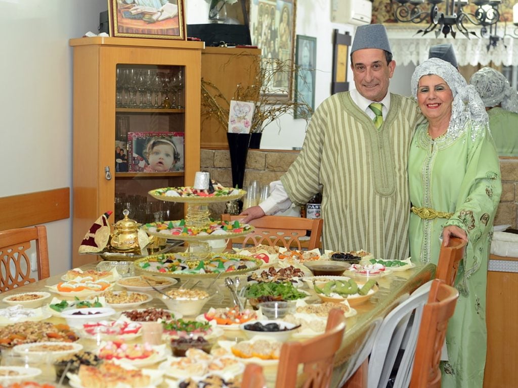 couple standing behind table of moroccan food