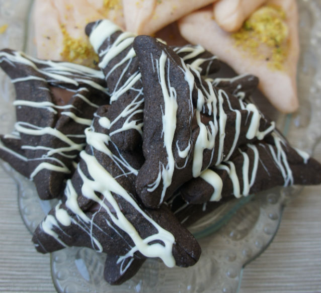 chocolate hamantaschen with white chocolate drizzle on top